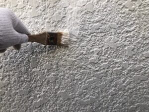 外壁に白いペンキを刷毛で塗装
