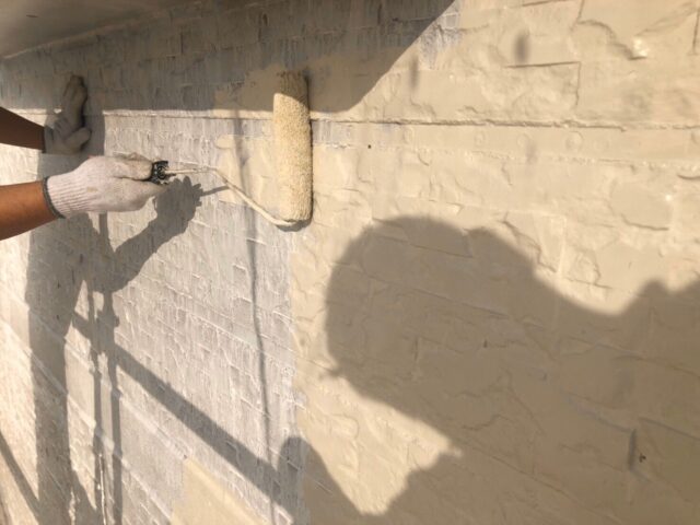 外壁に塗装中の職人が持つ塗装ローラー