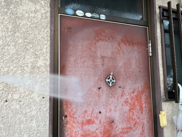 高圧洗浄される三鷹市のアパートのドア