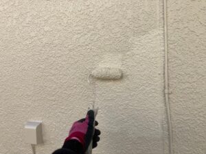 ローラーで仕上げの塗装をされる外壁