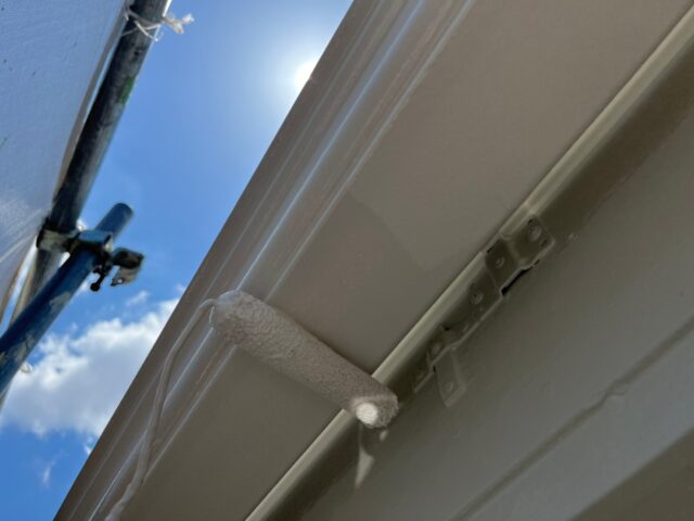 ローラーで白く塗装される三鷹市の住宅の雨樋