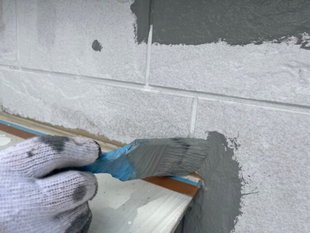 ハケでグレーに塗装される三鷹市の住宅の外壁