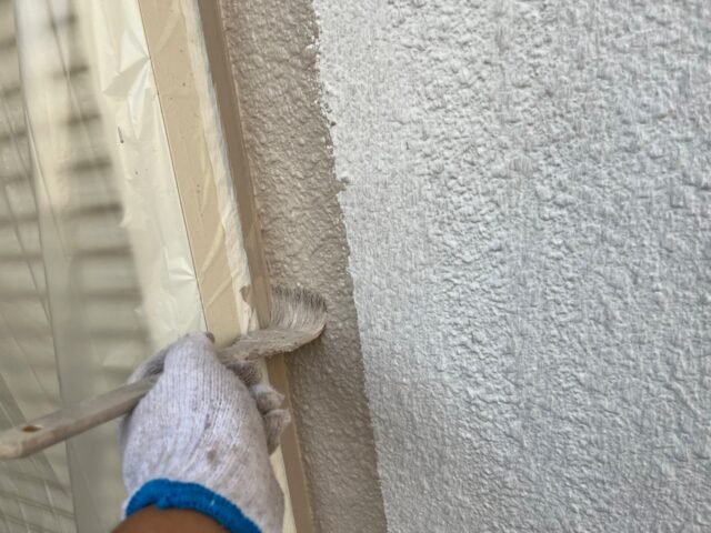 ハケで縁を丁寧に塗装される三鷹市の住宅の外壁