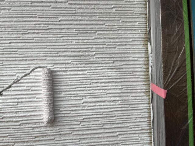 ローラーで白く塗られる武蔵野市の住宅の外壁