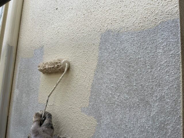 ローラーで中塗りされる世田谷区の住宅の外壁