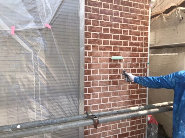 職人の手によってクリア塗装を塗られる調布市の住宅の外壁