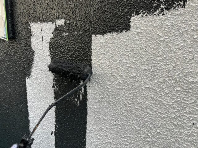 ローラーで黒く塗装される三鷹市の住宅の外壁