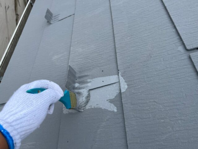 ハケでグレーに塗装される武蔵野市の住宅の屋根