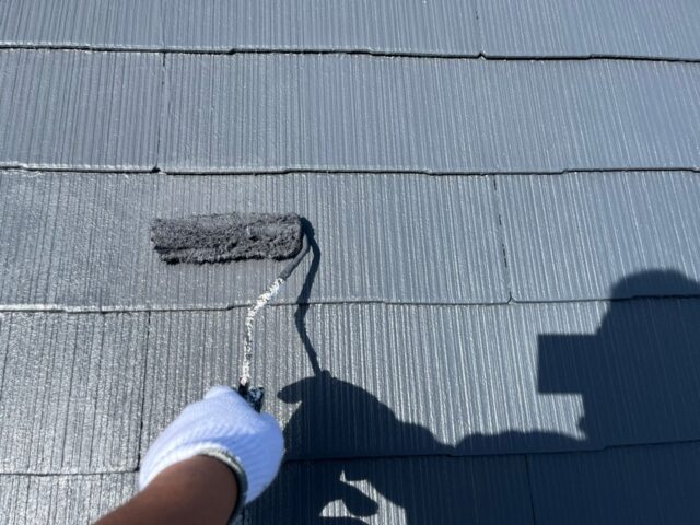 職人の手によってローラーで塗装される三鷹市の住宅の屋根
